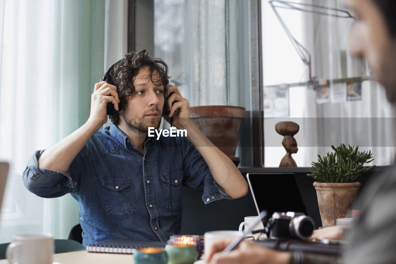 Creative man wearing headphones while sitting at table in office