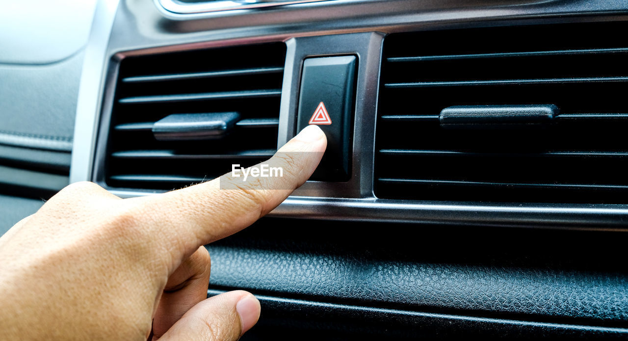 Close-up of hand pressing push button in car