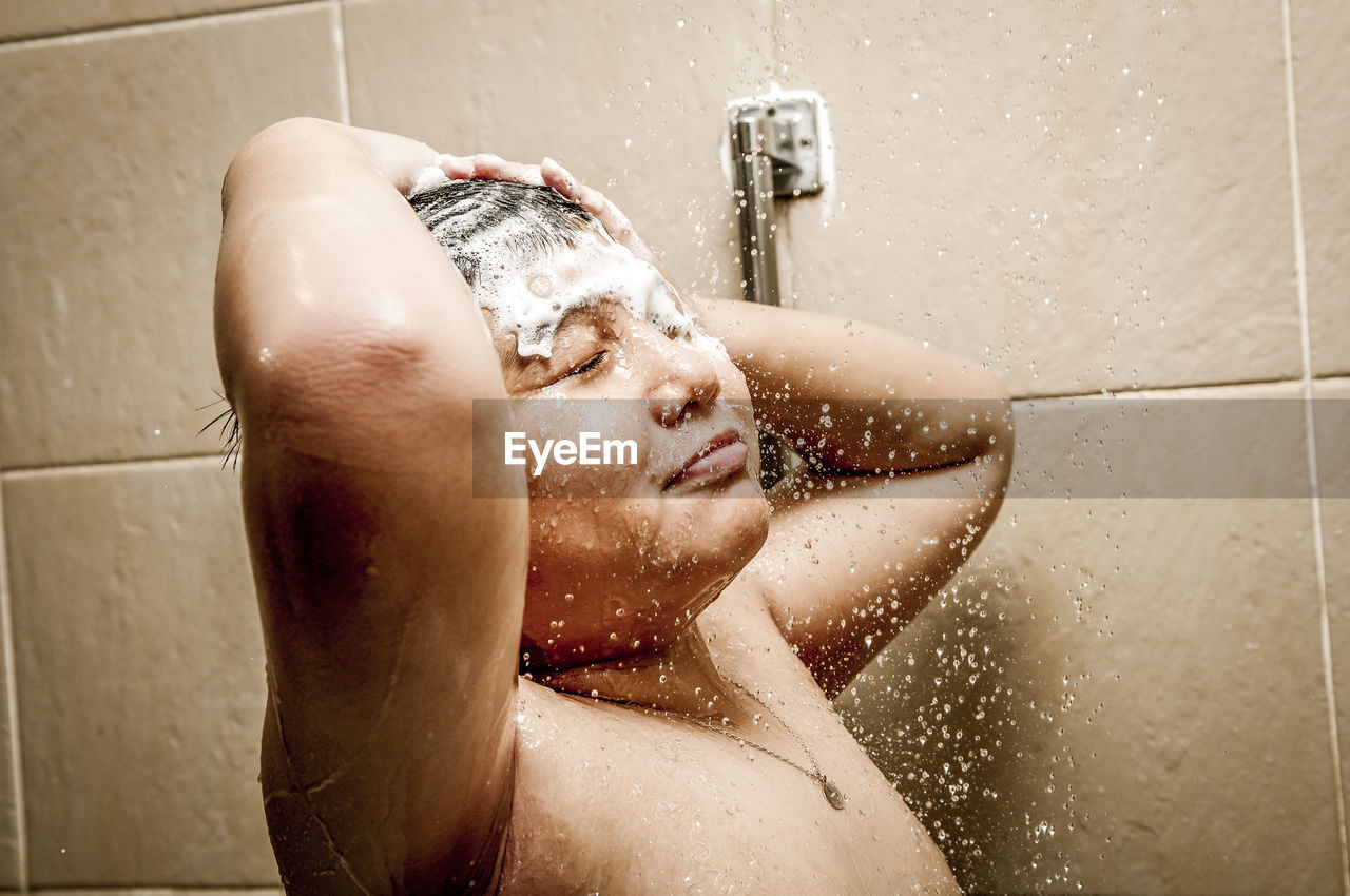 Shirtless boy taking bath in bathroom