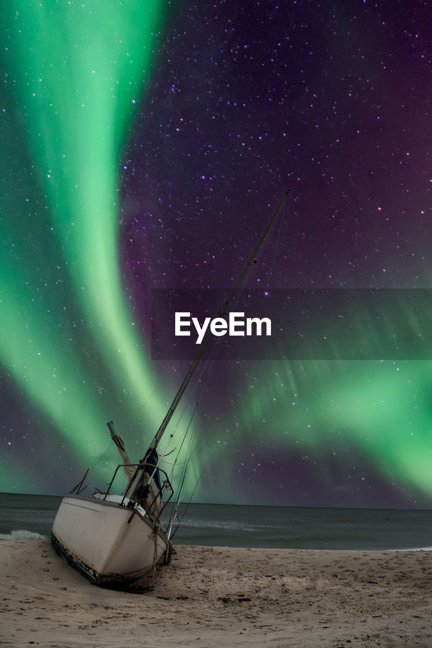 Aurora borealis over a shipwreck off the coast of uttakleiv beach in norway