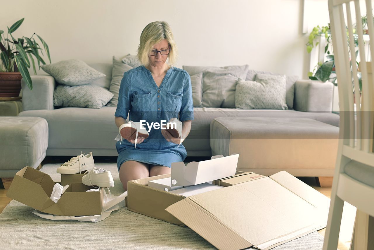 Woman holding shoes while kneeling at home