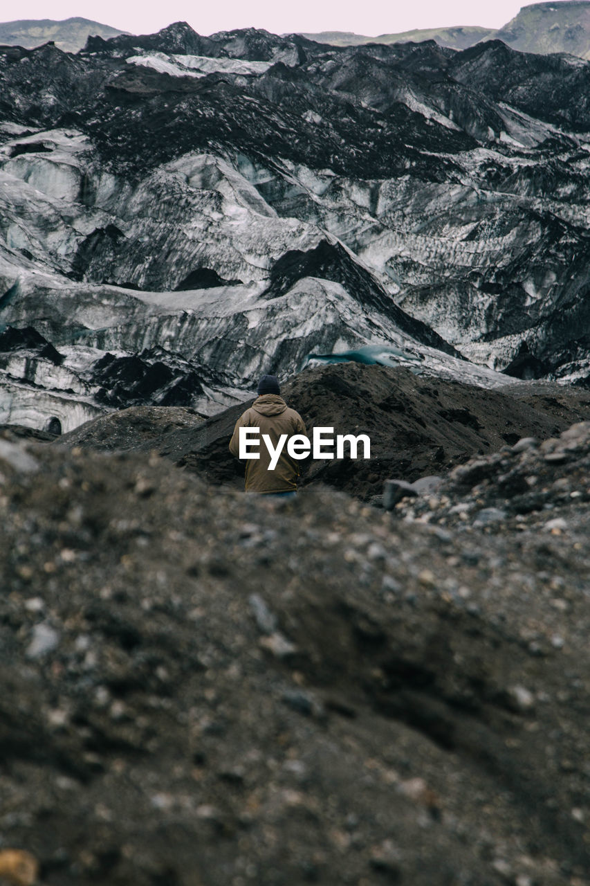 Rear view of man standing amidst rocky mountains