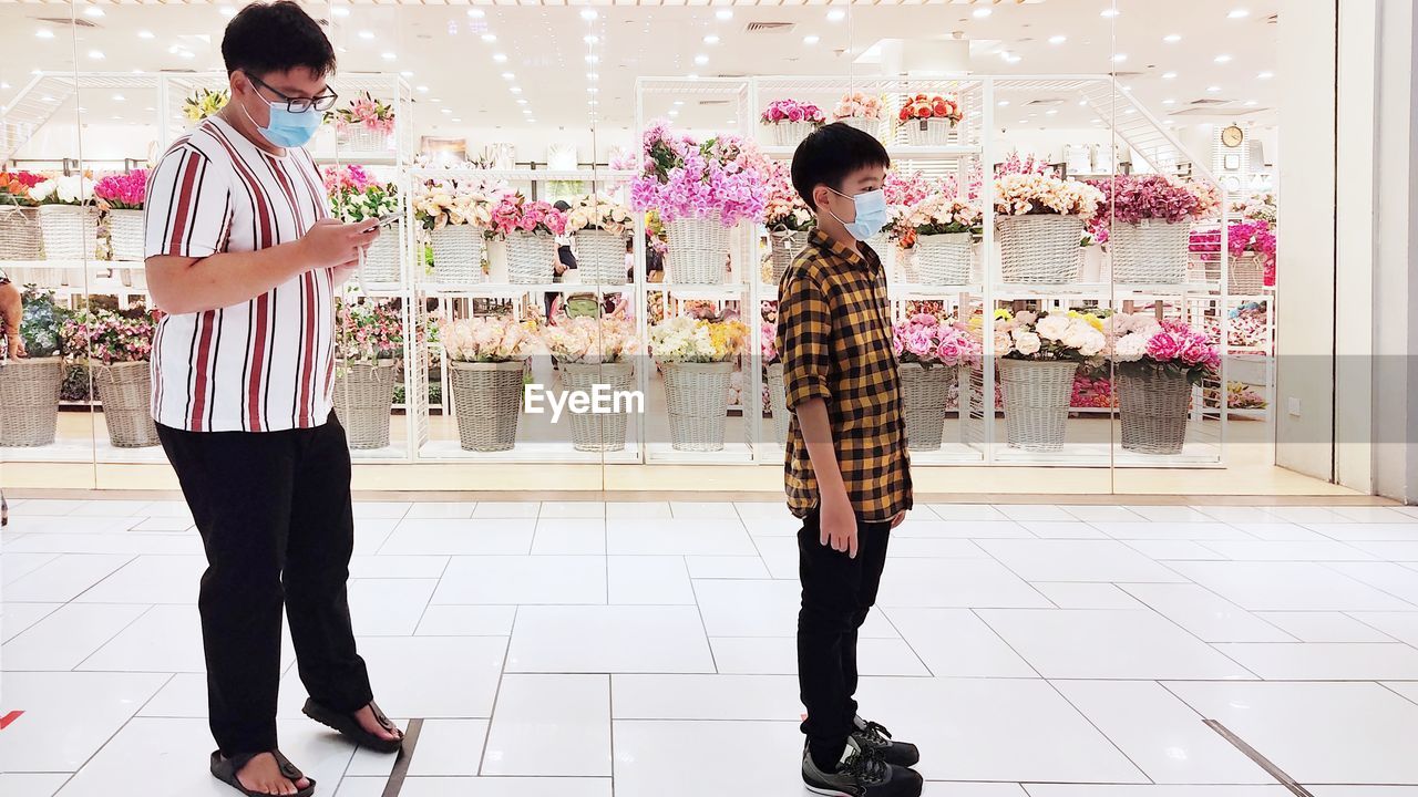  full length of friends standing in line outside a store at shopping mall.