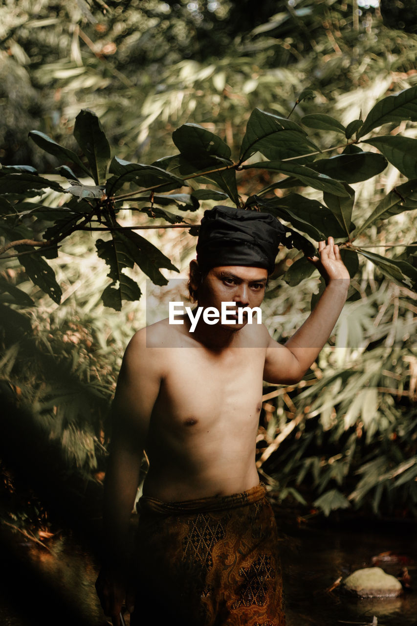 Portrait of young man standing against plants