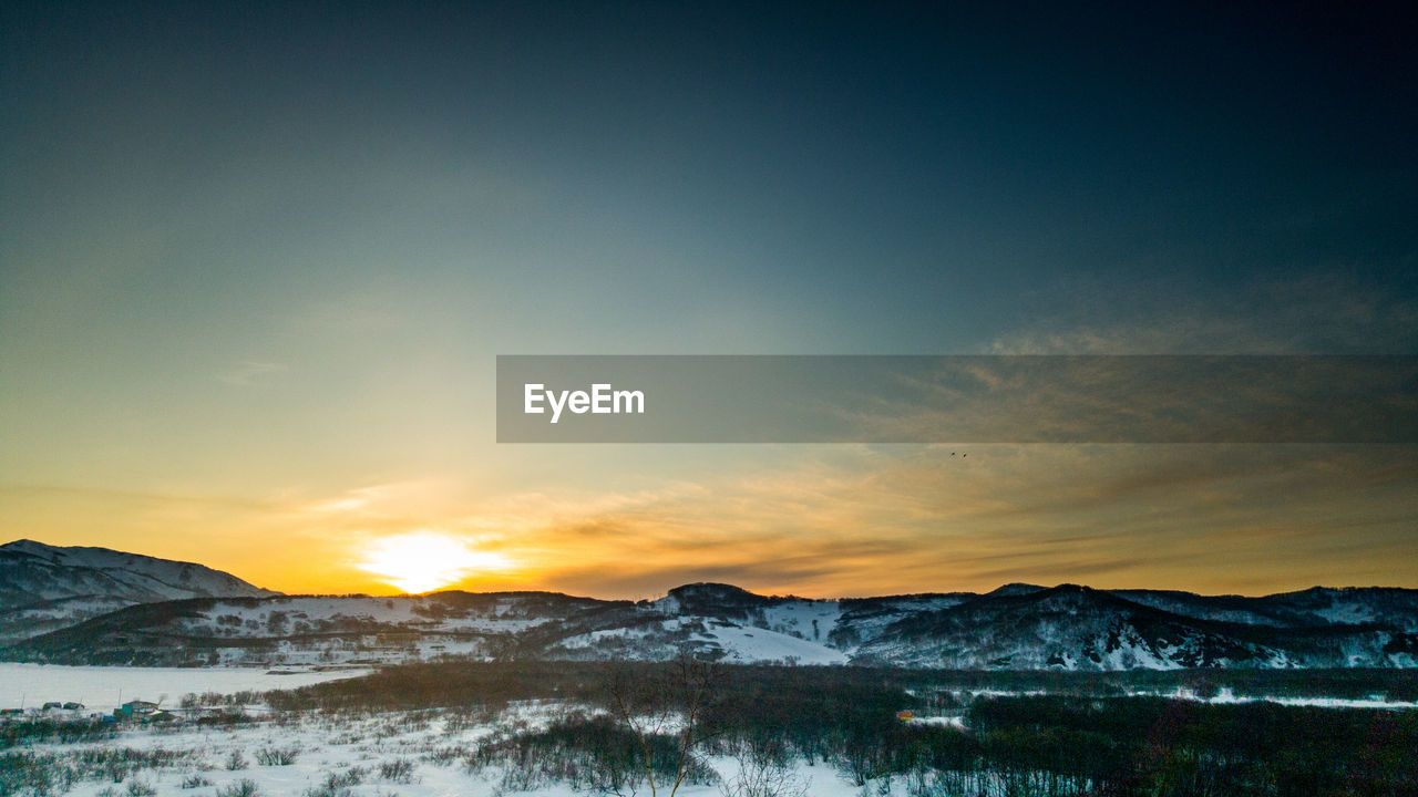 Scenic view of snowcapped mountains against sky during sunset