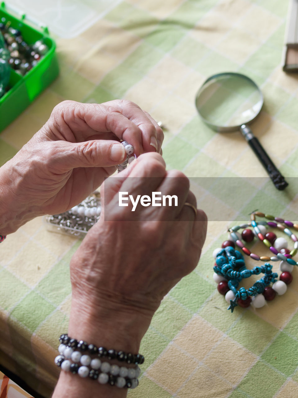 High angle view of woman making bracelet on table