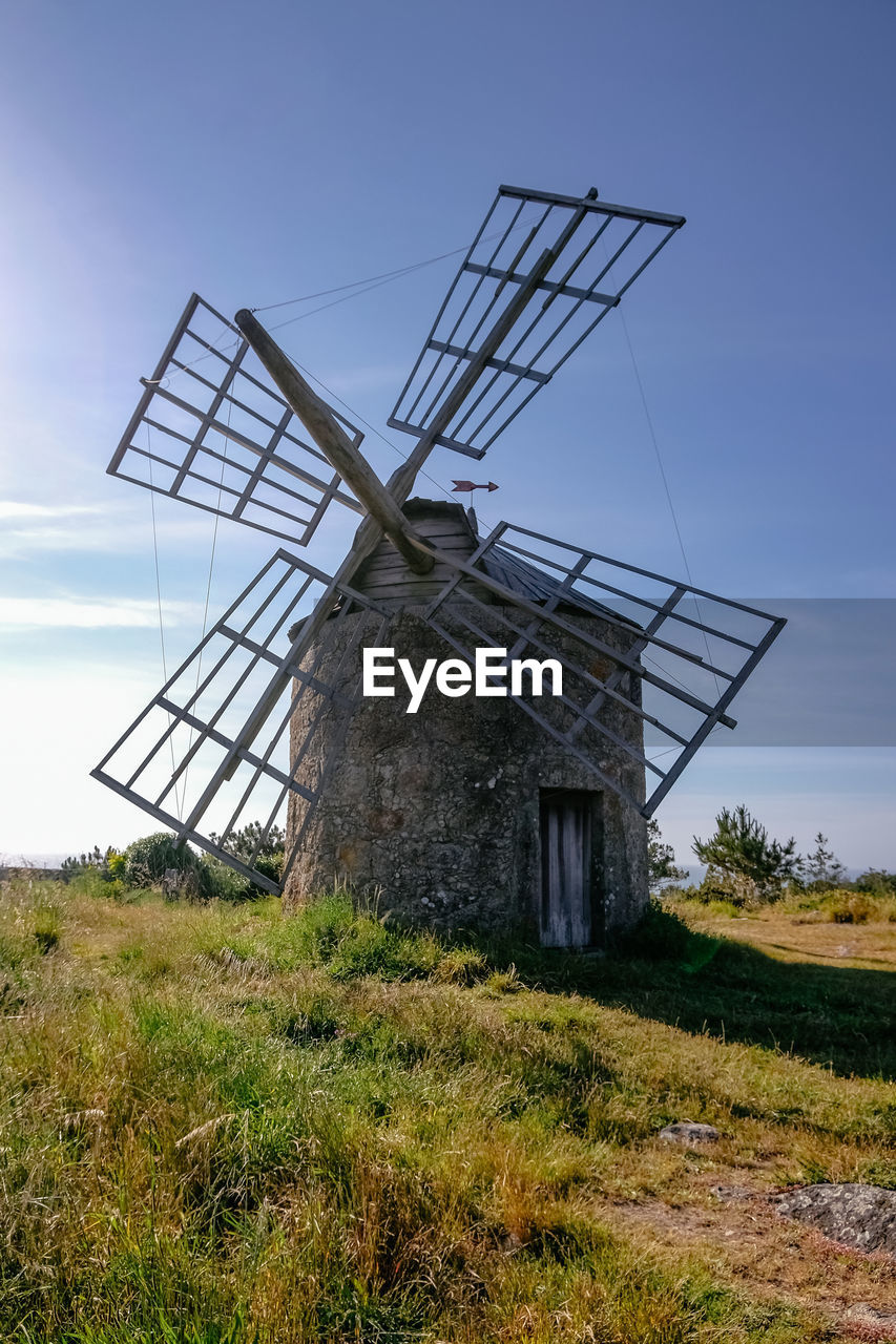LOW ANGLE VIEW OF TRADITIONAL WINDMILL ON FIELD