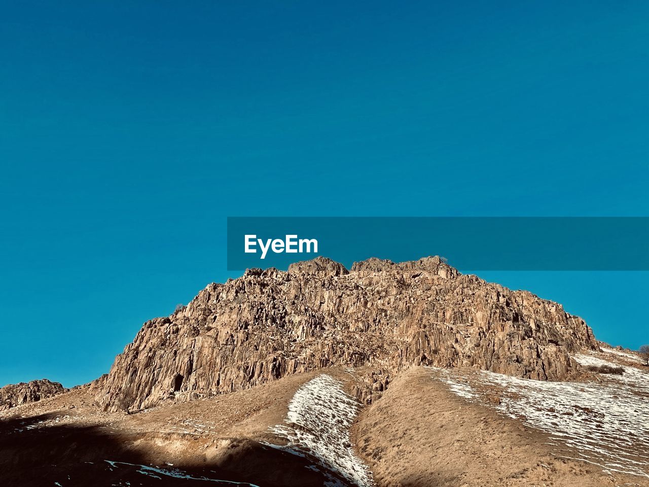 Low angle view of rock formation against clear blue sky