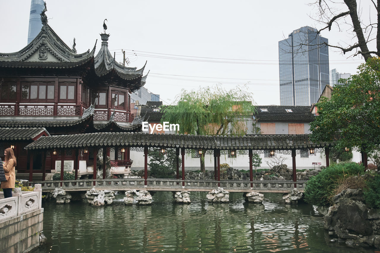 BRIDGE OVER RIVER AMIDST BUILDINGS IN CITY