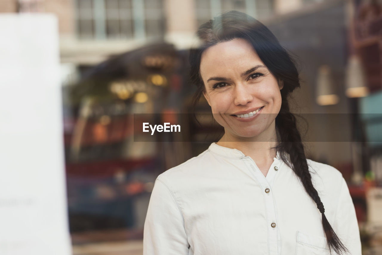 Portrait of smiling customer seen through glass window