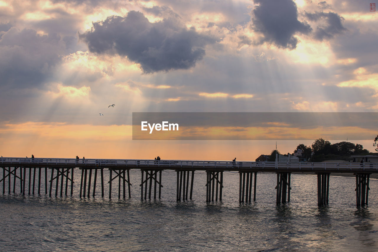 PIER OVER SEA AGAINST ORANGE SKY