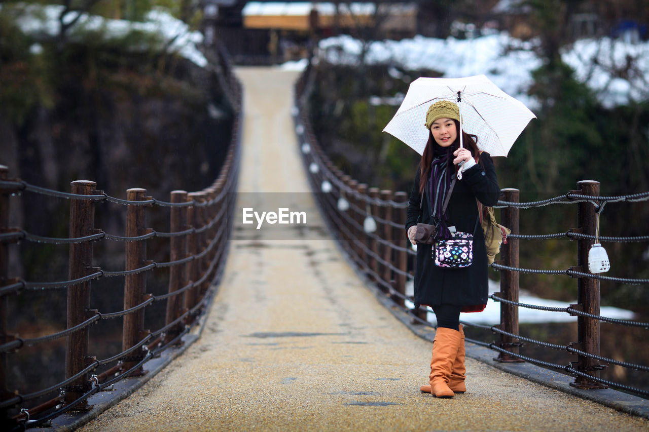 Portrait of woman standing on bridge during winter