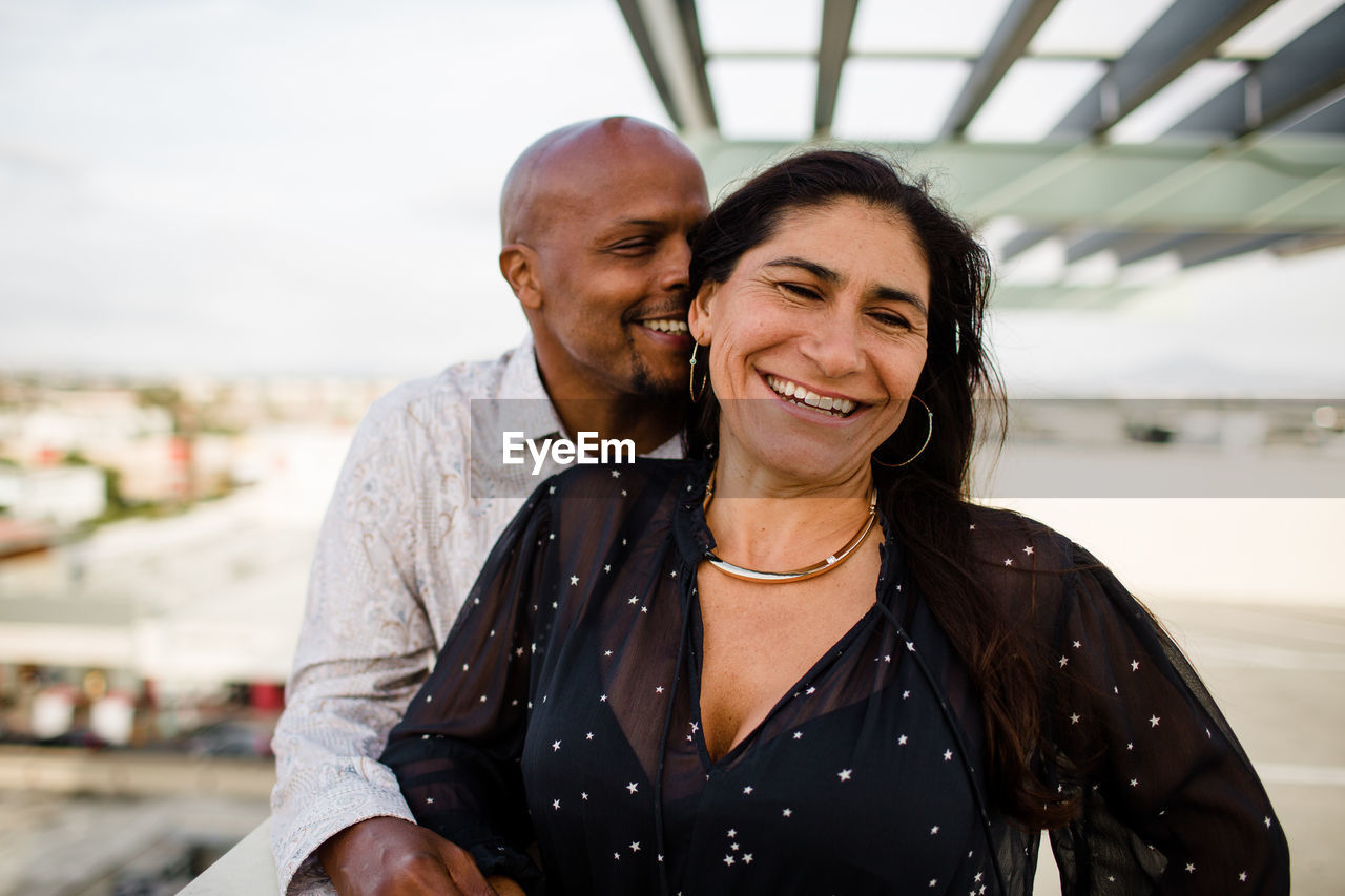 Multiracial late forties couple embracing at sunset in san diego