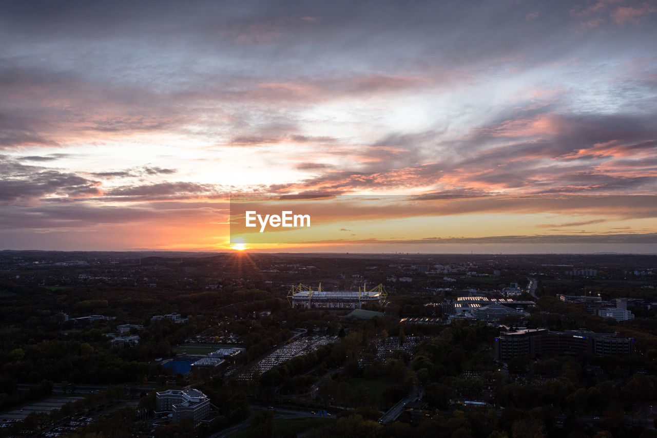 HIGH ANGLE VIEW OF ILLUMINATED CITYSCAPE AT SUNSET