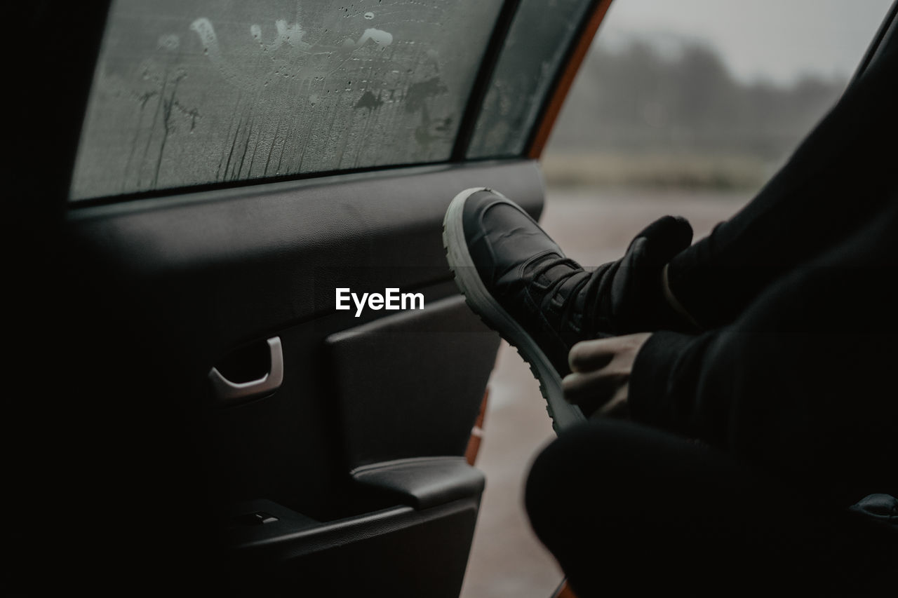 Low section of man wearing shoe sitting in car