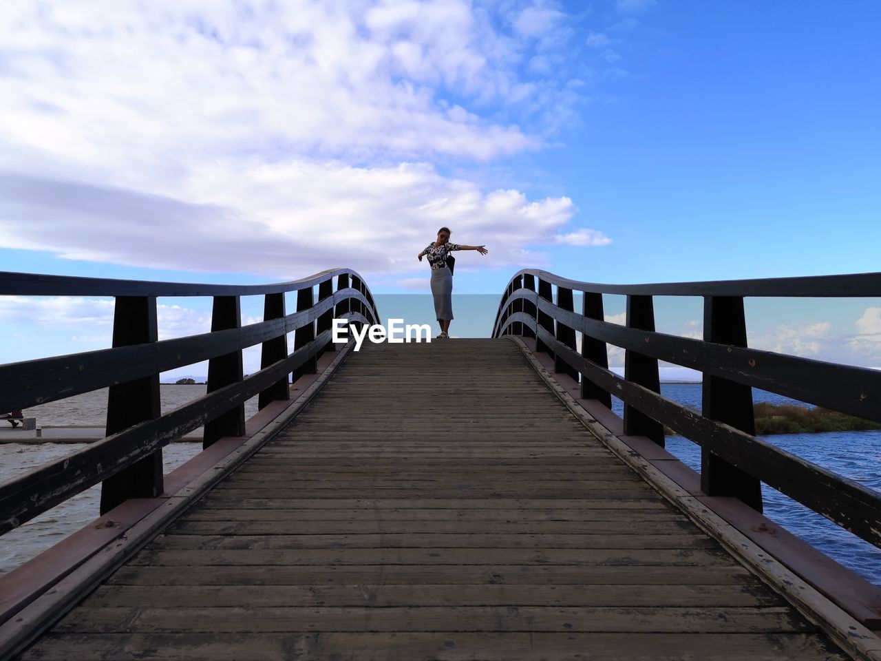 MAN STANDING ON FOOTBRIDGE