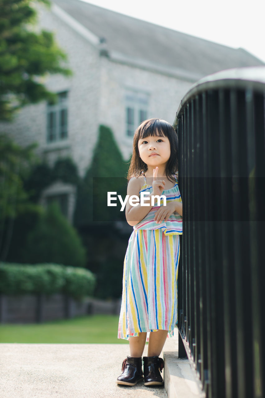 Full length of girl standing by railings