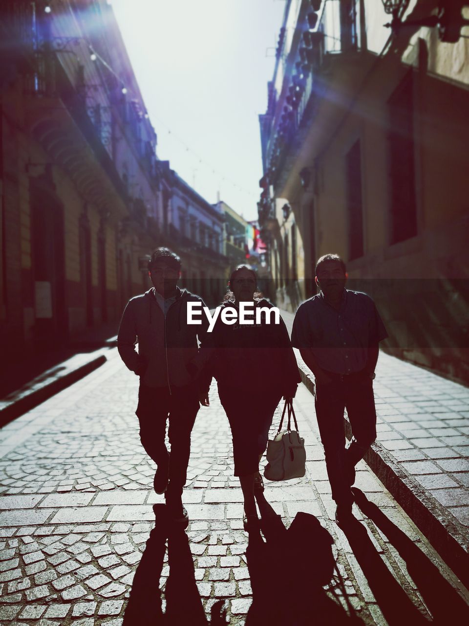 Full length of family walking on street amidst buildings in city during sunny day