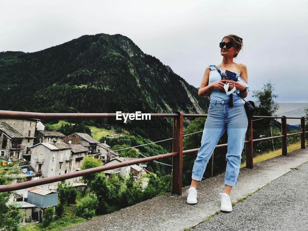 Full length of woman looking away while standing by railing against mountain