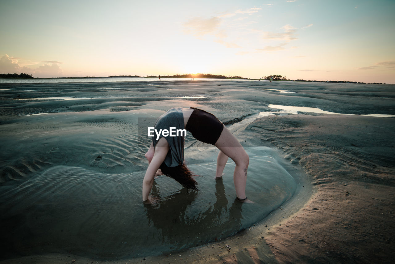 Woman doing back bend on beach