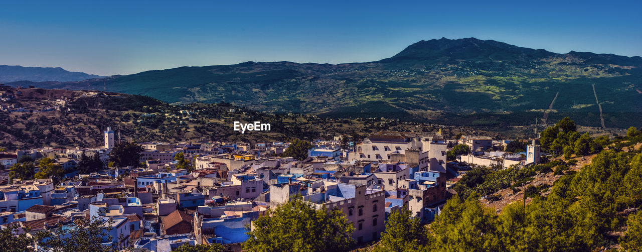 Aerial view of houses and mountains against clear blue sky