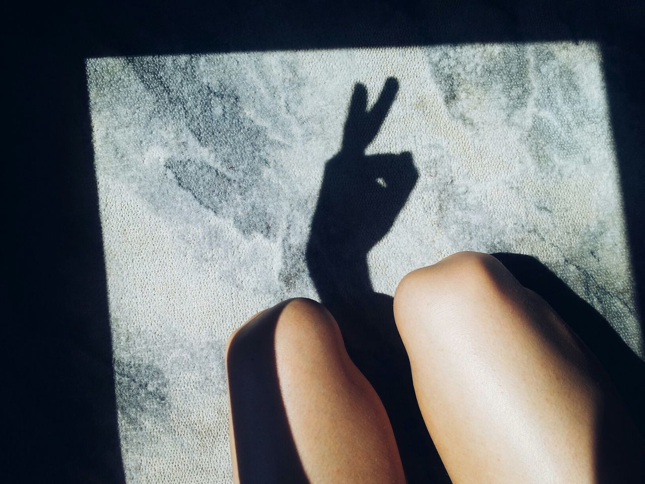 High angle view of young woman's shadow gesturing on floor