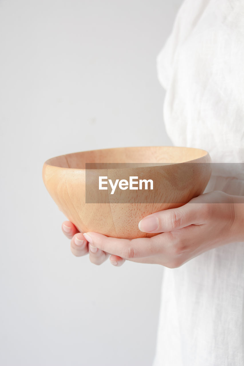 Asian woman hands holding wooden bowl.