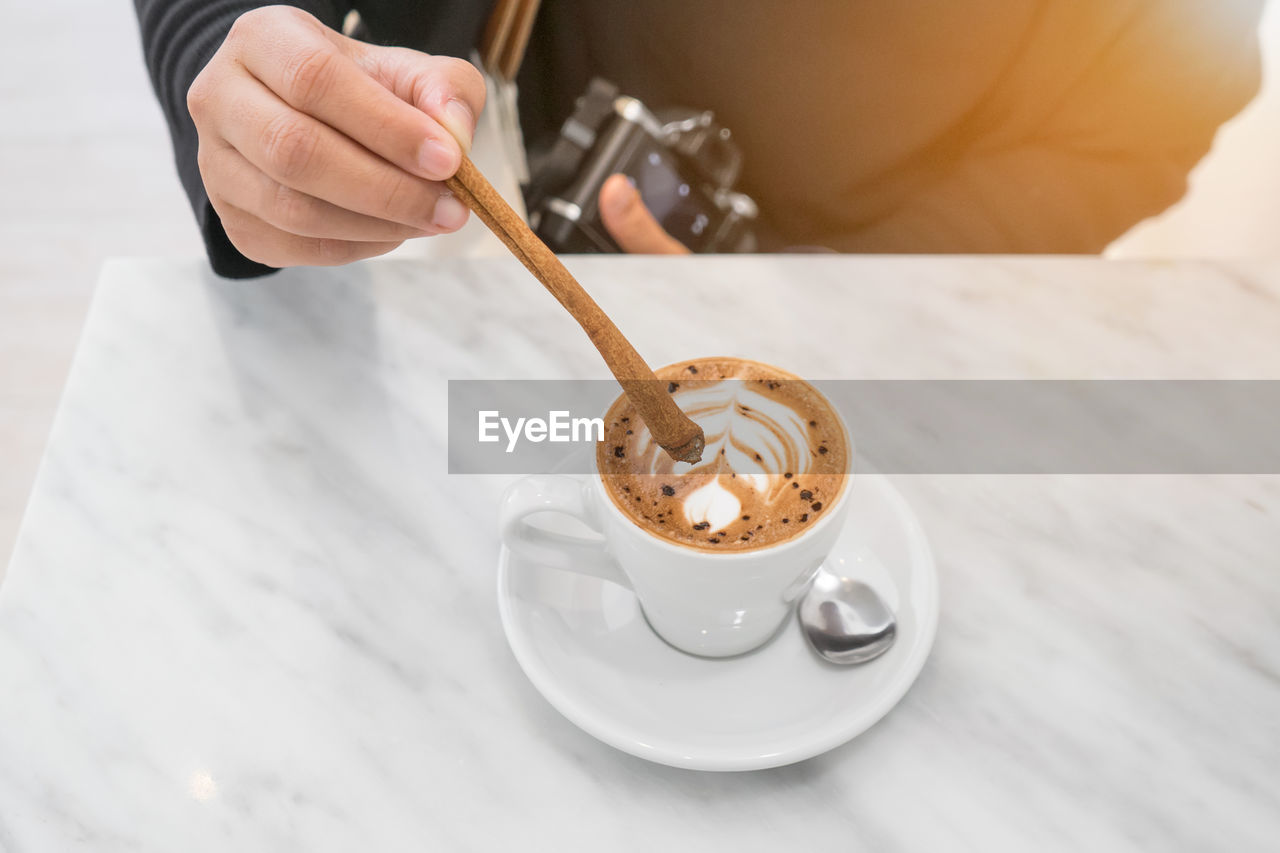 Hand holding coffee cup on table