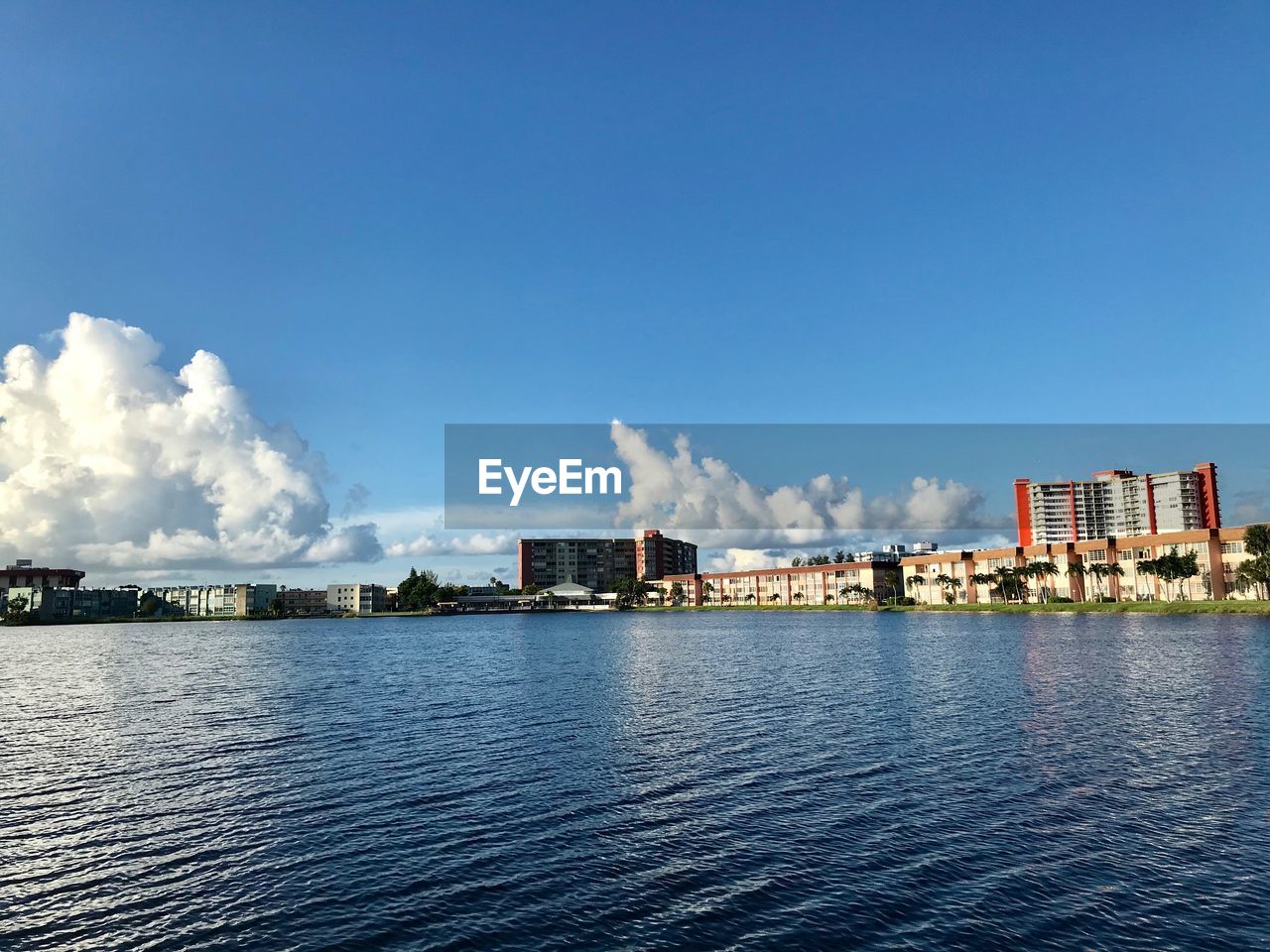 River by buildings against blue sky