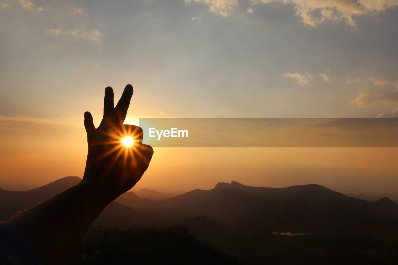 SILHOUETTE HAND AGAINST SUNSET SKY