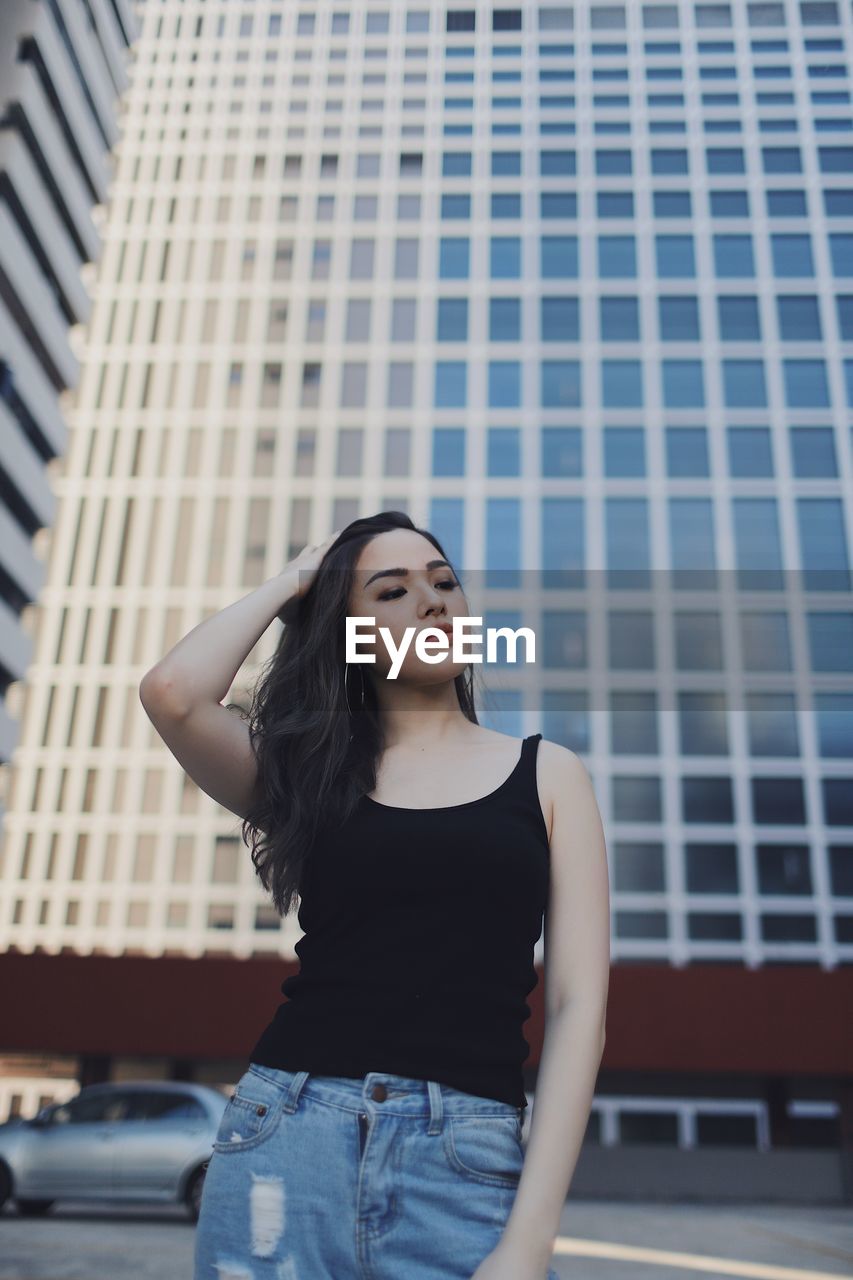 Young woman standing against buildings in city