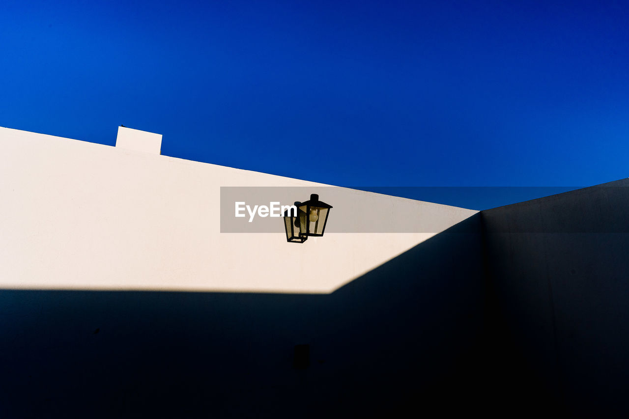 Low angle view of a lamp on building against clear blue sky