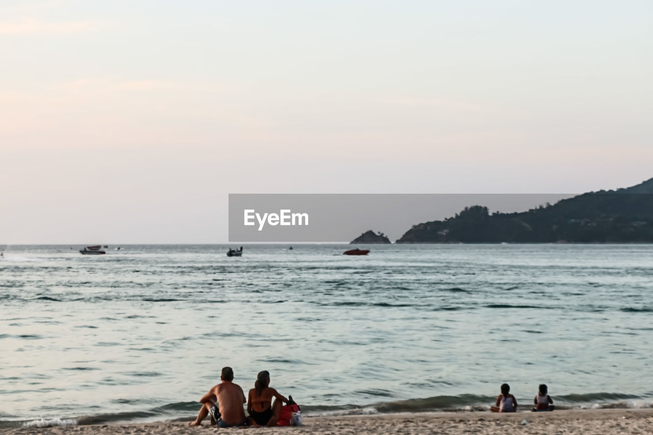 PEOPLE AT BEACH AGAINST SKY