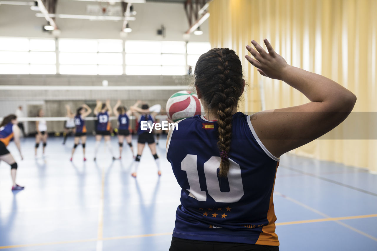 Competitive female volleyball player serving ball while tourname