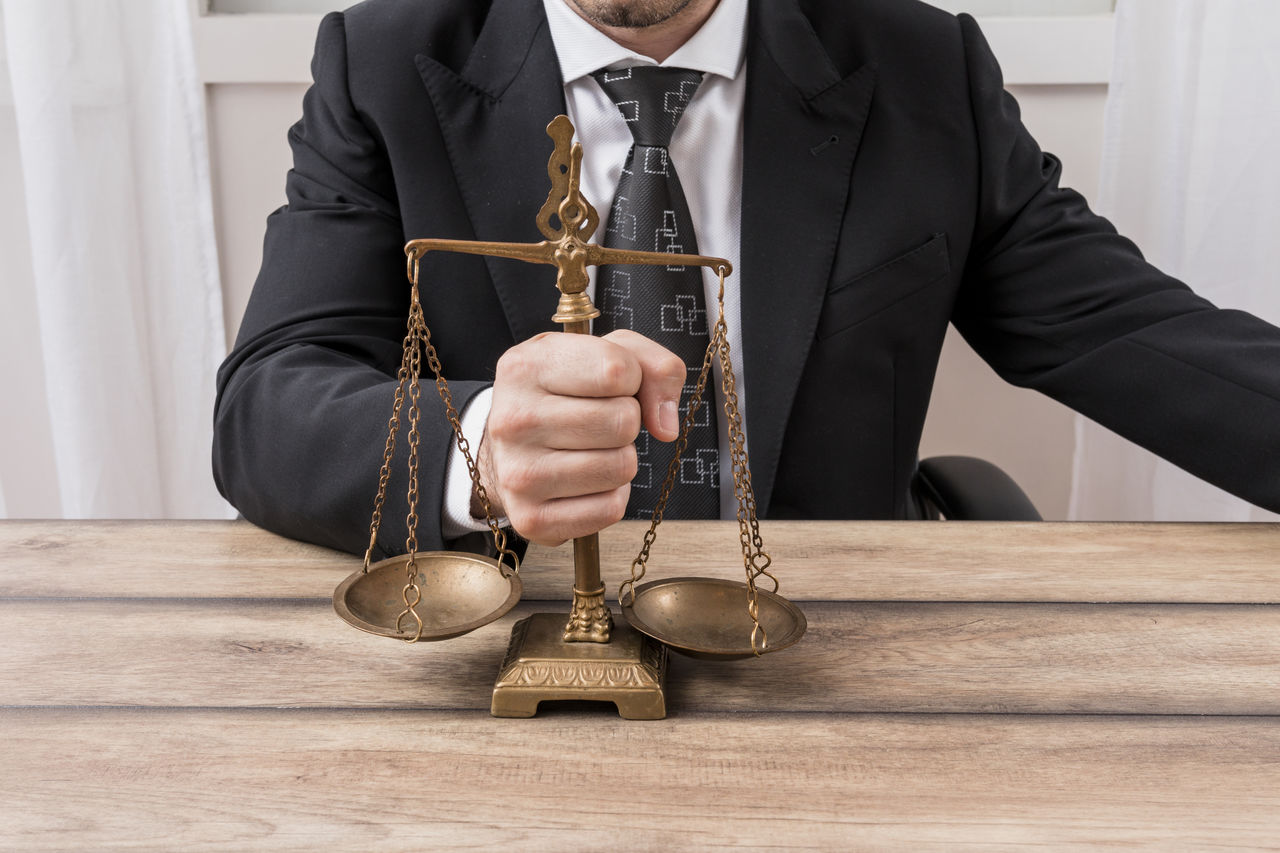 Midsection of lawyer holding weigh scale