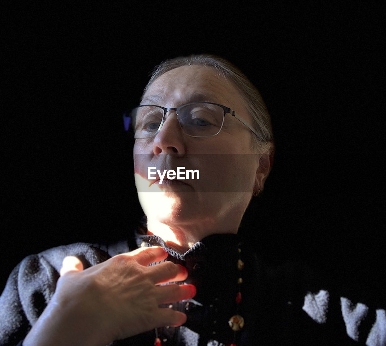 CLOSE-UP PORTRAIT OF MAN WITH EYEGLASSES ON BLACK BACKGROUND