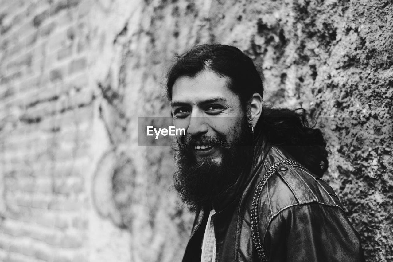 Portrait of happy man leaning on wall