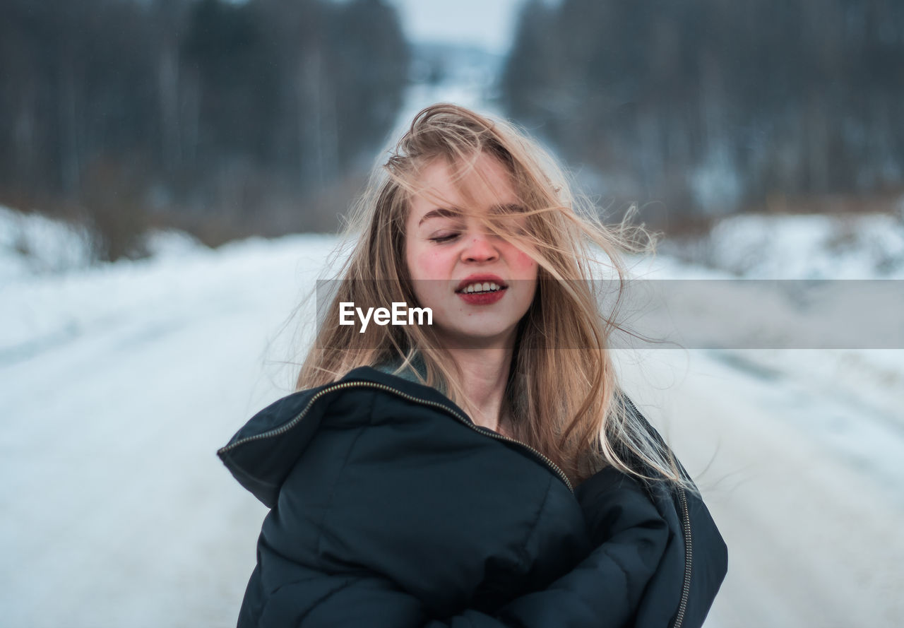 Young woman with blond hair standing on snow