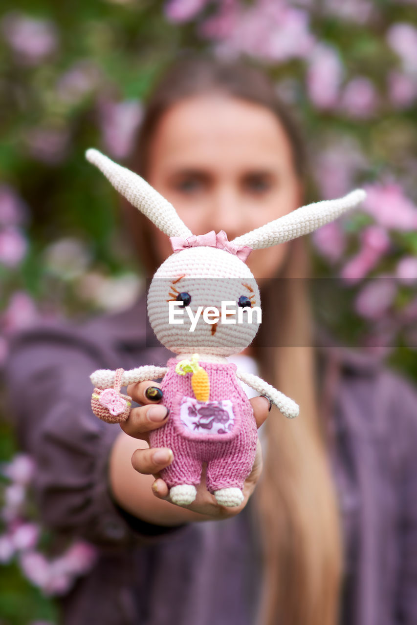 Knitted toy hare in the hands of a young girl.
