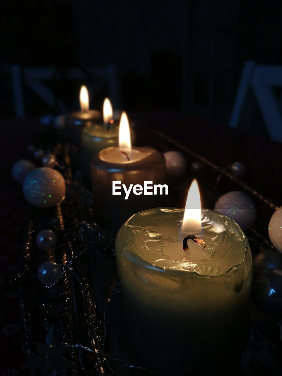 CLOSE-UP OF LIT CANDLES BURNING IN DARK