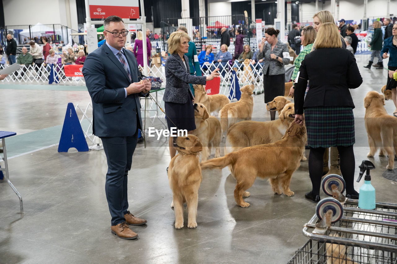 PEOPLE STANDING WITH DOGS AT MARKET