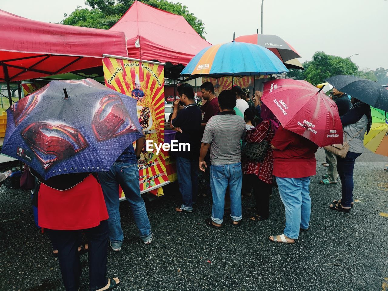 REAR VIEW OF PEOPLE WALKING ON STREET DURING RAIN