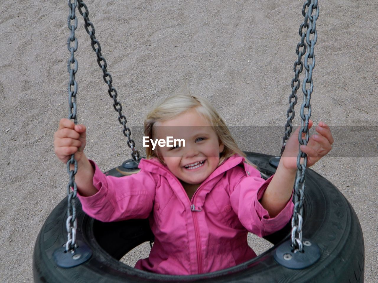 Portrait of smiling girl sitting on swing at playground