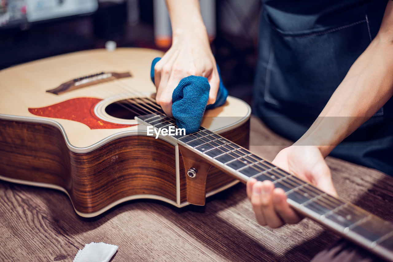 Midsection of man repairing guitar