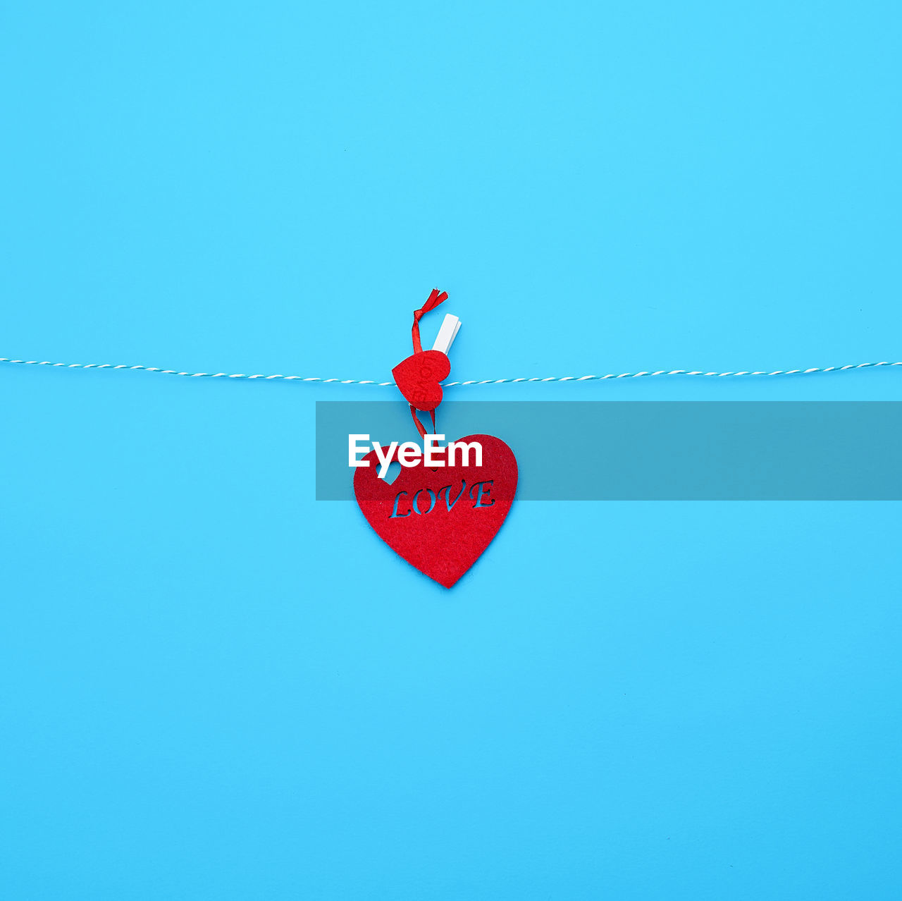 Close-up of heart shape hanging on rope against blue background