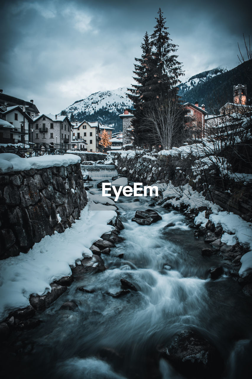 Snow covered houses and trees against sky