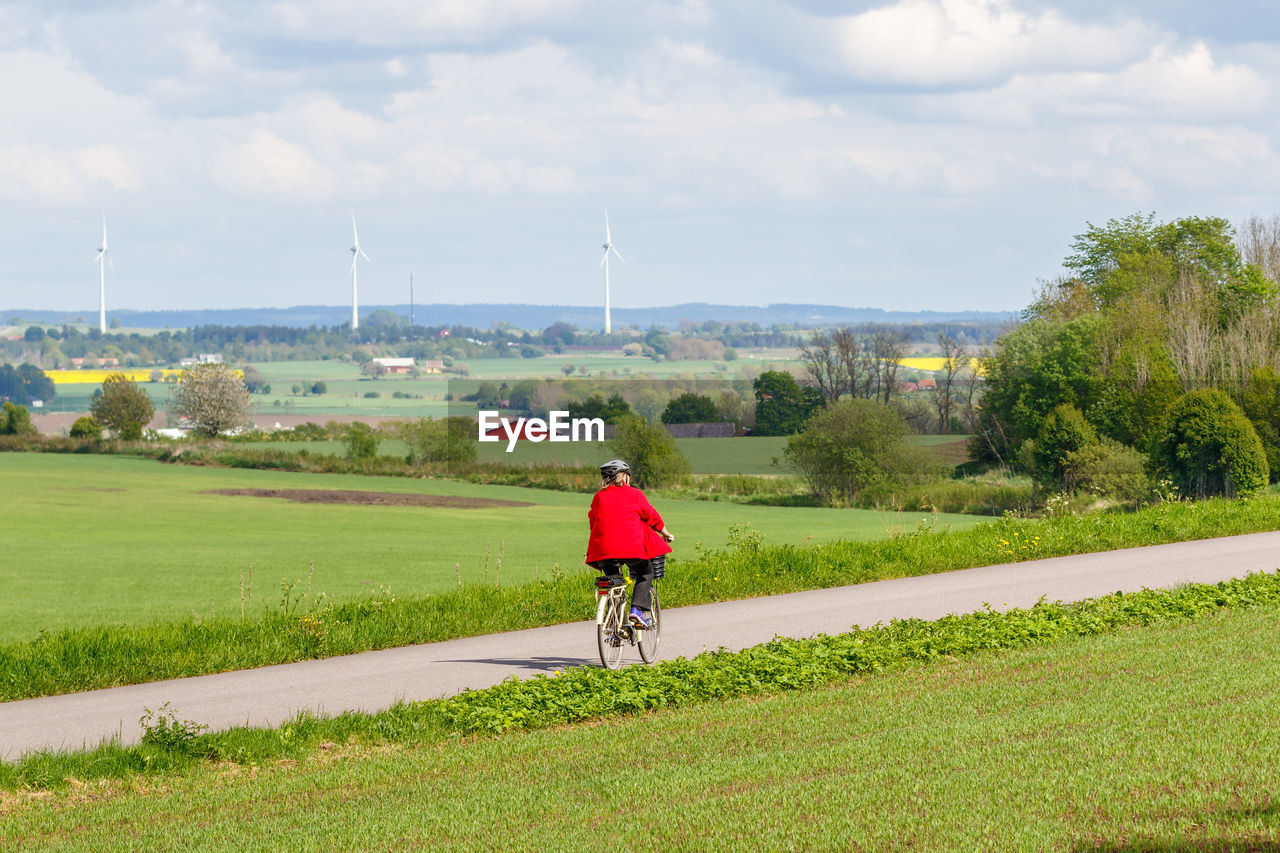 REAR VIEW OF WOMAN RIDING BICYCLE ON FIELD