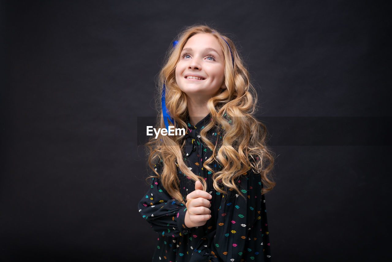 Close-up portrait gentle young caucasian girl with loose wavy hair on a black