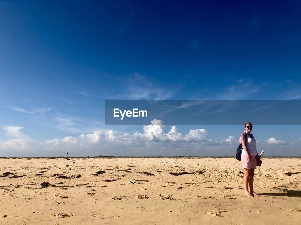 Full length of woman standing on sand against sky