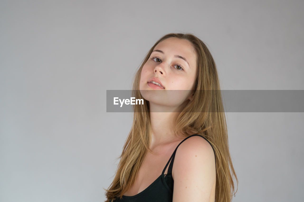 PORTRAIT OF A BEAUTIFUL YOUNG WOMAN AGAINST WHITE BACKGROUND